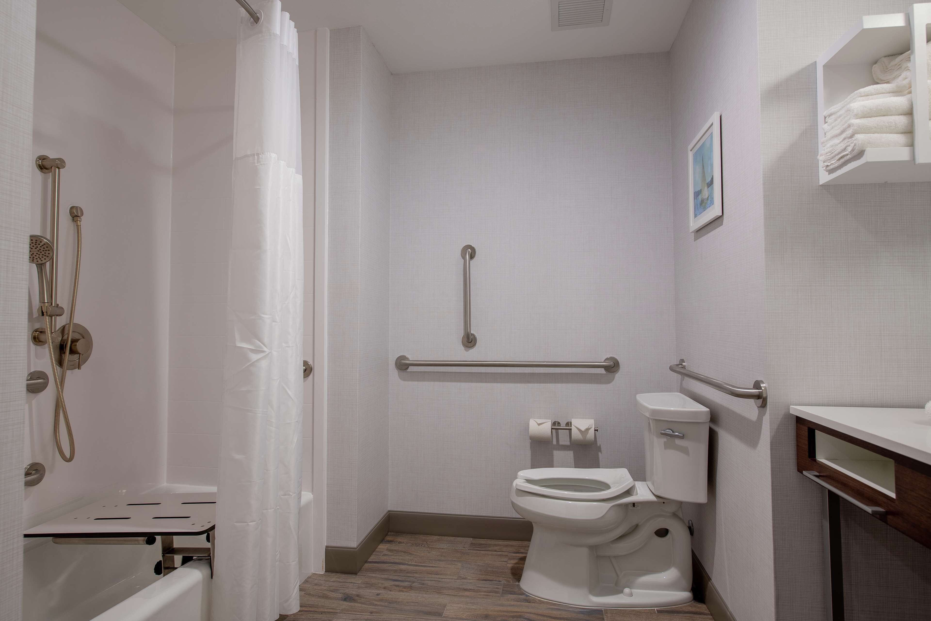A bathroom with a shower, toilet, and grab bars.