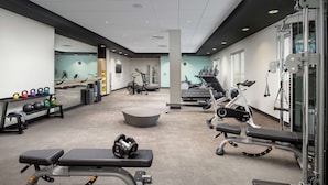 Un gimnasio con varios equipos de ejercicio, incluyendo cintas de correr, máquinas de pesas y mancuernas.