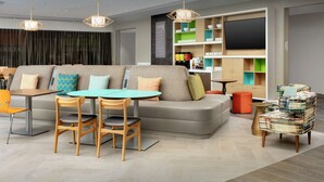 Una sala de estar moderna con un sofá, sillas, una mesa y un televisor.