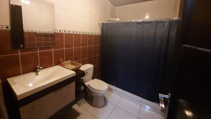 Baño con lavabo, inodoro y cortina de ducha.