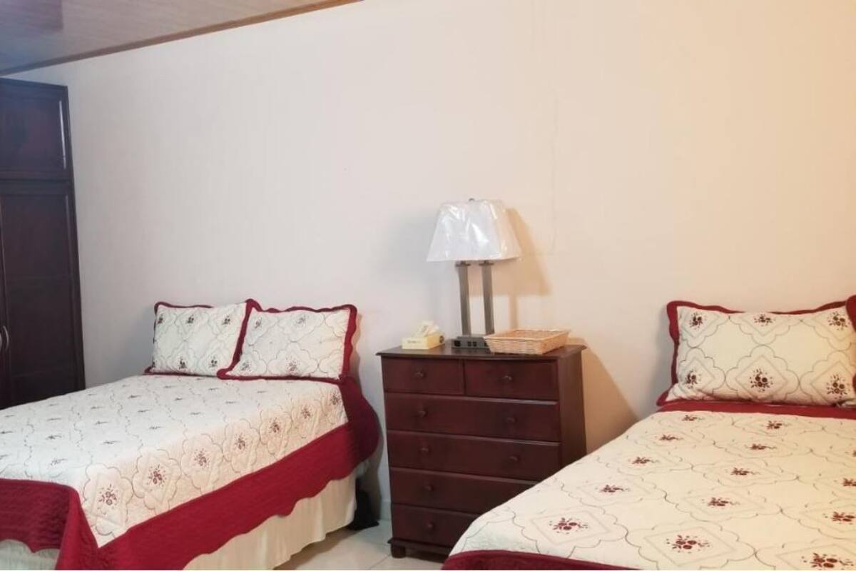 A bedroom with two beds, a wardrobe, a dresser, and a bedside lamp.