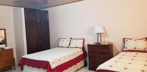 A bedroom with two beds, a wardrobe, a dresser, and a bedside lamp. - B&B Lodgings (24 de Diciembre)