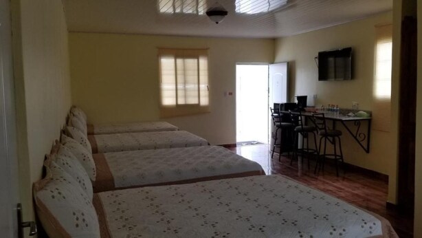 Una habitación con dos camas, un escritorio con sillas, una televisión y una ventana con persianas.