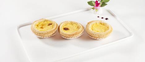 Three custard tarts on a white rectangular plate.