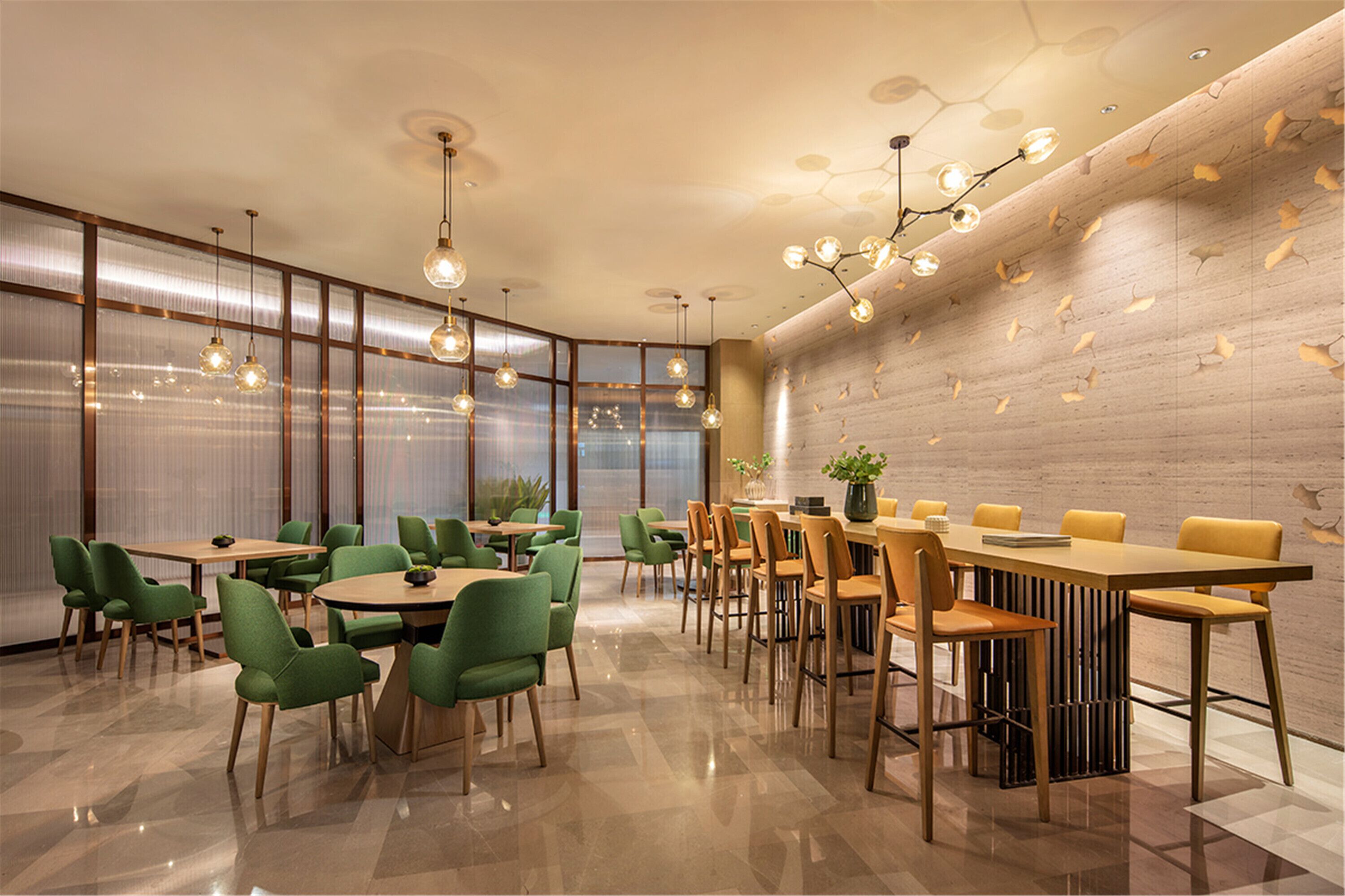 A modern dining area with green and yellow chairs, wooden tables, and a decorative ceiling light fixture.