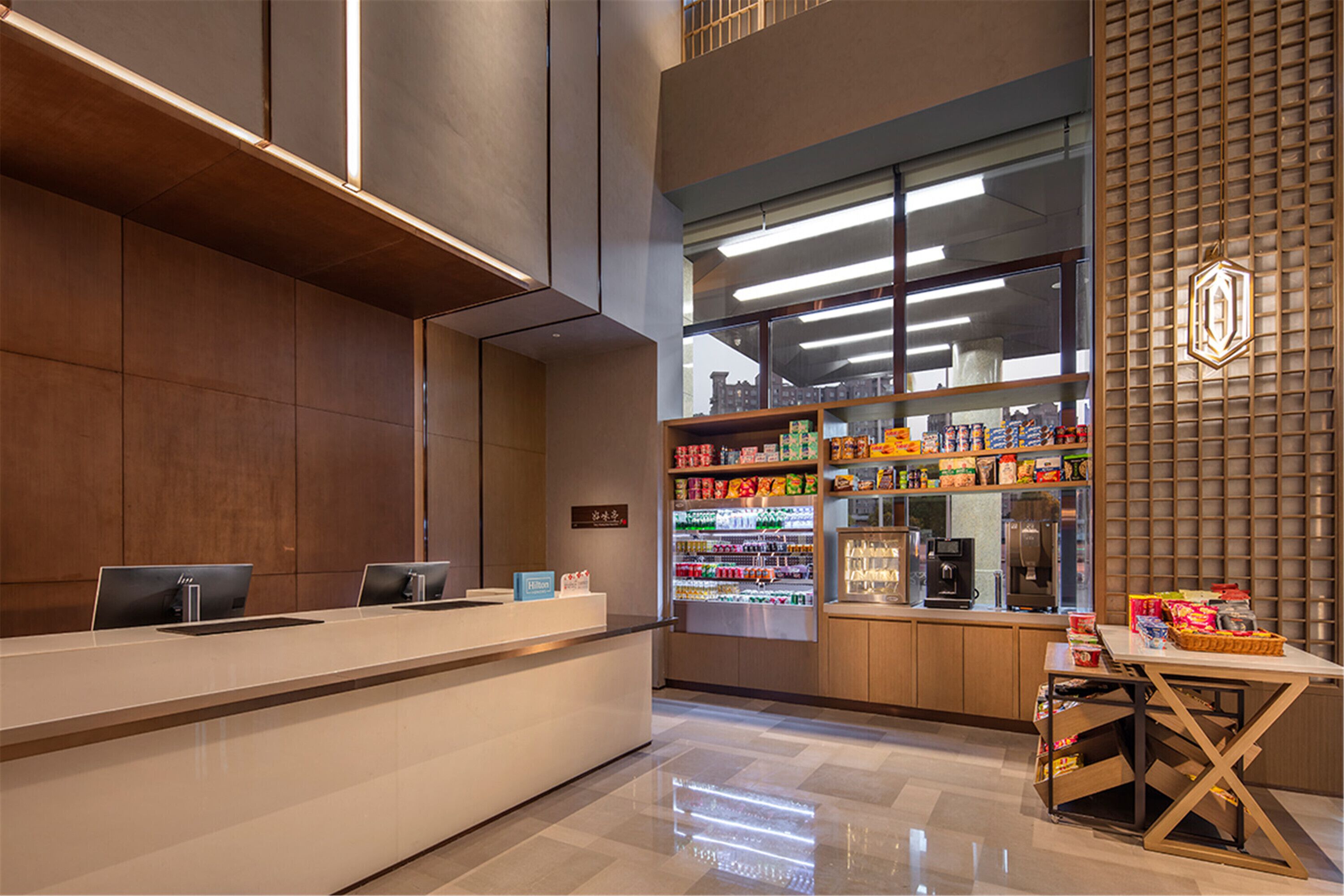 Un área de recepción moderna con mostrador, computadoras, dispensador de bebidas y máquina de café.