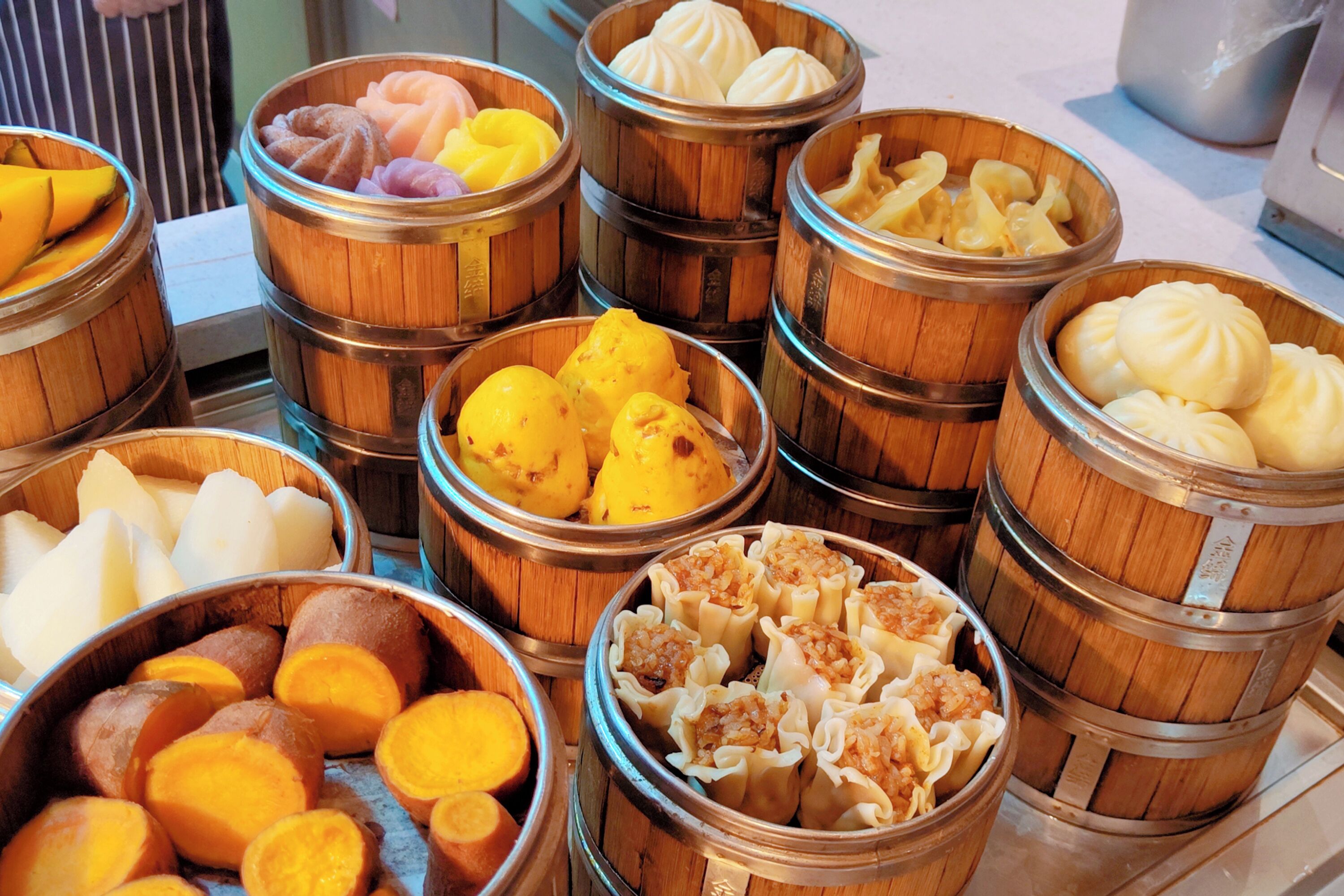 A variety of steamed buns and pastries in wooden baskets.
