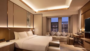Una habitación de hotel moderna con una cama grande, un sofá, un escritorio y un televisor.