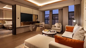 Una sala de estar moderna con un televisor de pantalla plana, un sofá, una mesa de centro y un comedor con mesa y sillas.