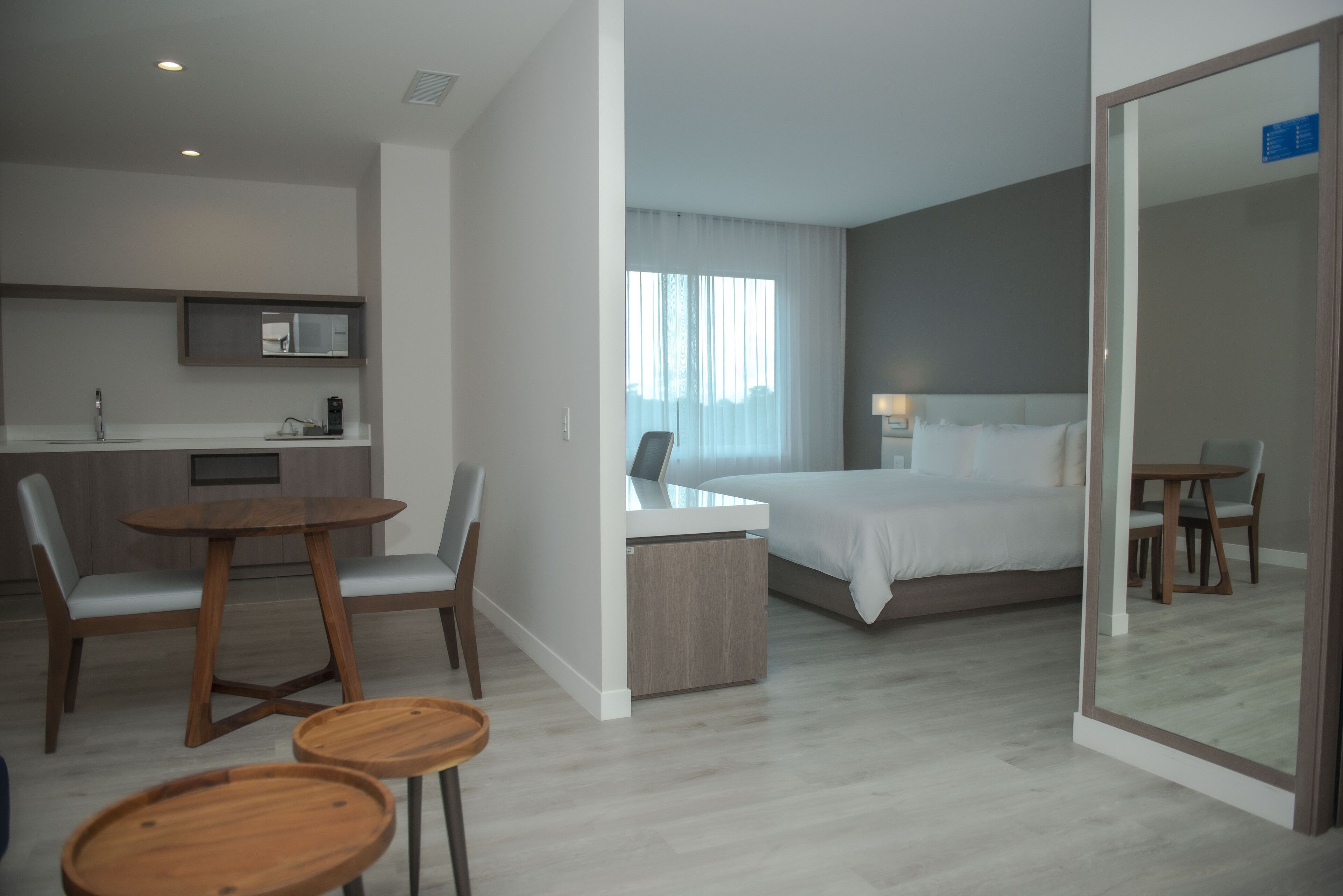 A modern hotel room with a bed, a desk, and a seating area.