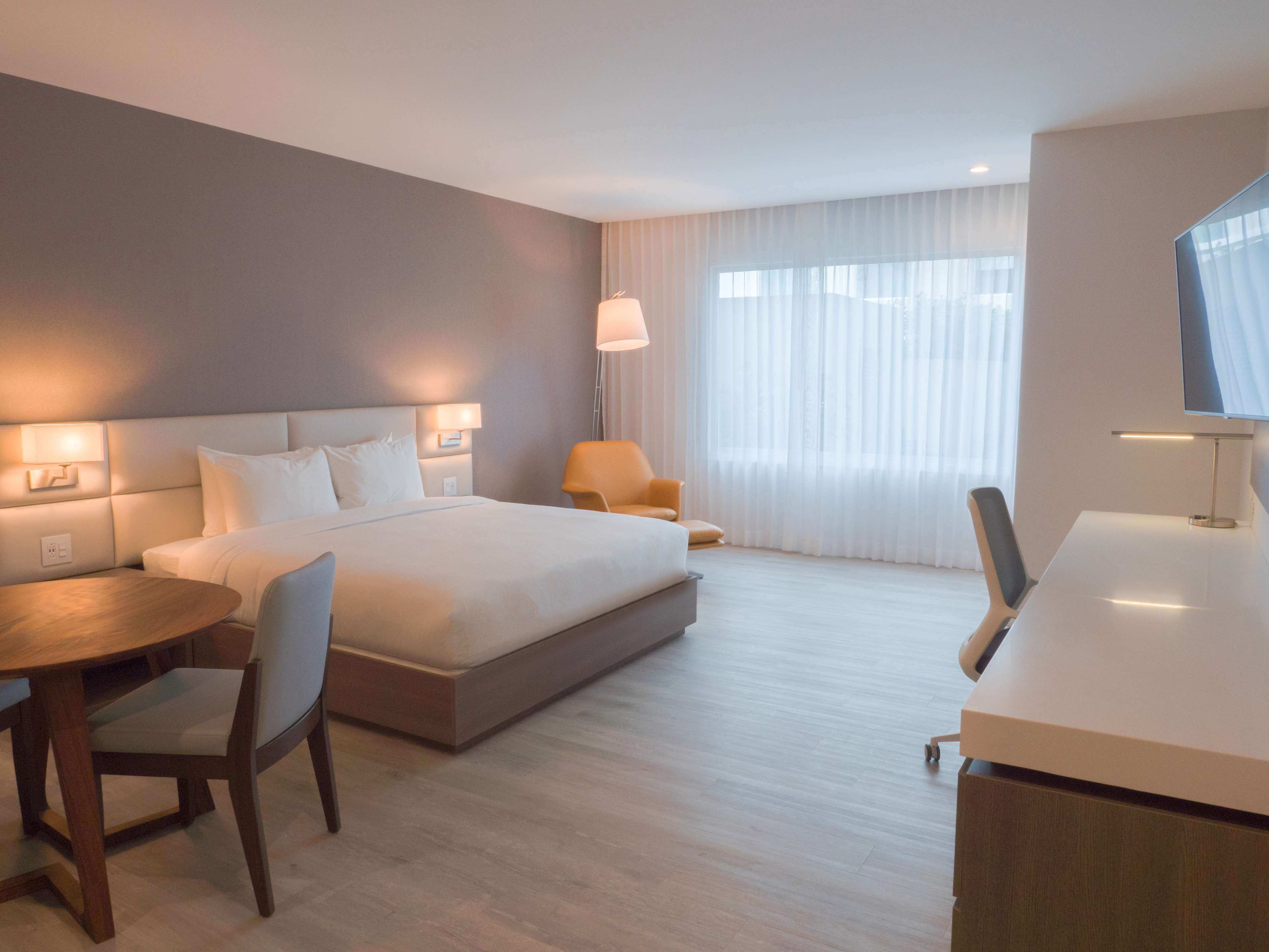 Une chambre d’hôtel moderne équipée d’un grand lit, d’un bureau, d’une chaise et d’un téléviseur.