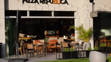 An outdoor seating area with tables and chairs in front of a building with a sign reading "PIZZA REPUBLICA".