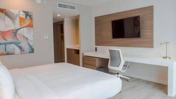 Un hotel moderno con una cama grande, un escritorio con una silla, un televisor de pantalla plana montado en la pared y un cuadro en la pared.