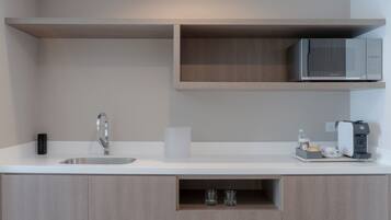 Een moderne keuken met een ingebouwde magnetron, een koffieapparaat en een spoelbak.