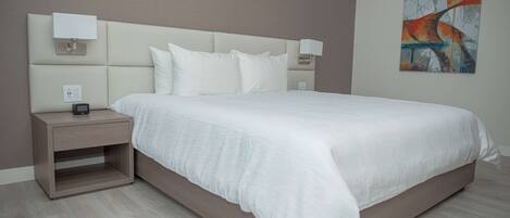 A modern bedroom with a large bed, bedside tables, and a wall-mounted artwork.