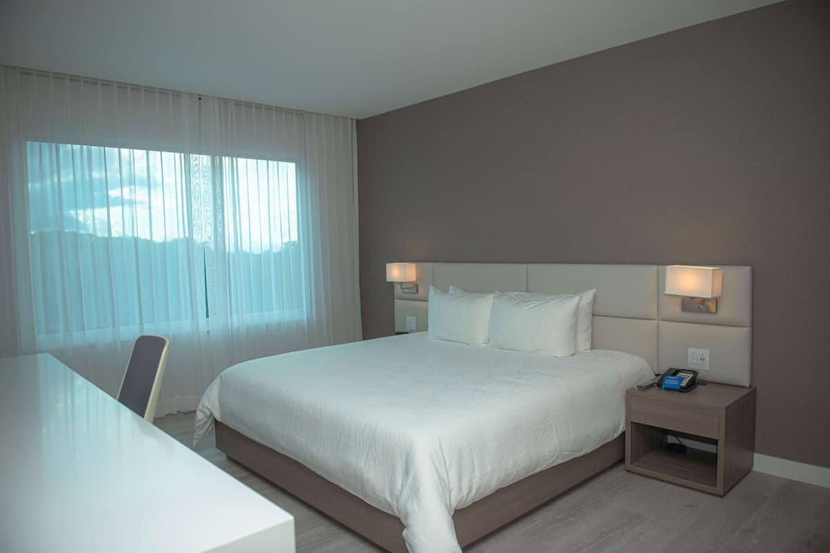 Una habitación de hotel con una cama grande, lámparas de noche, un escritorio y una silla.