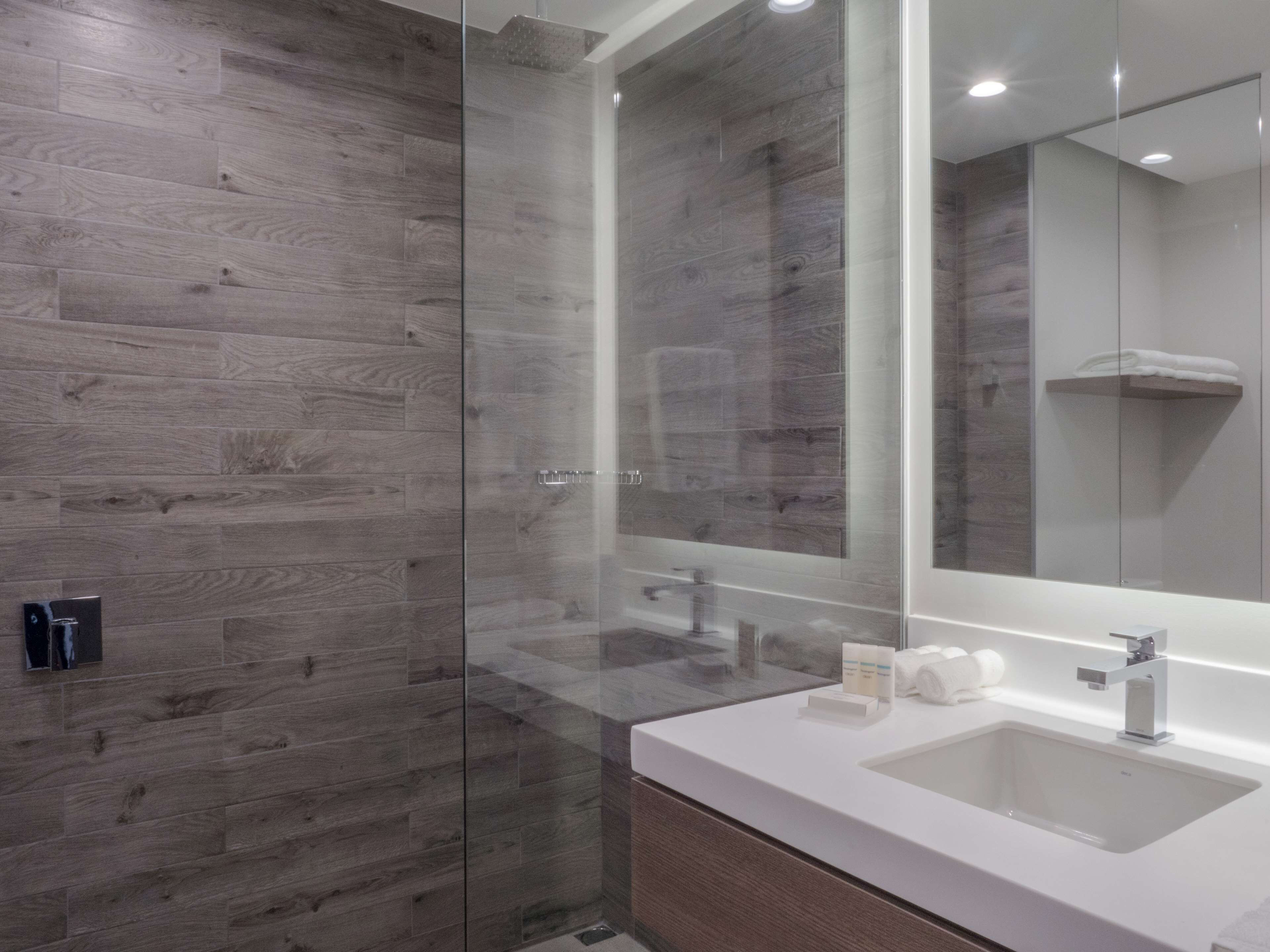Une salle de bain moderne avec une douche à parois de verre, un lavabo blanc et un grand miroir.