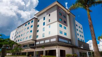 A modern multi-story hotel with a flat roof, multiple windows, and a visible entrance.