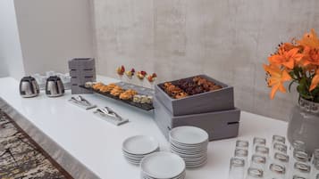 A buffet setup with various food items, serving trays, and a vase of flowers.