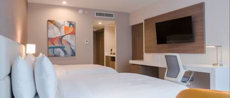 A modern hotel room with a large bed, a desk, a flat-screen TV, and a painting on the wall.
