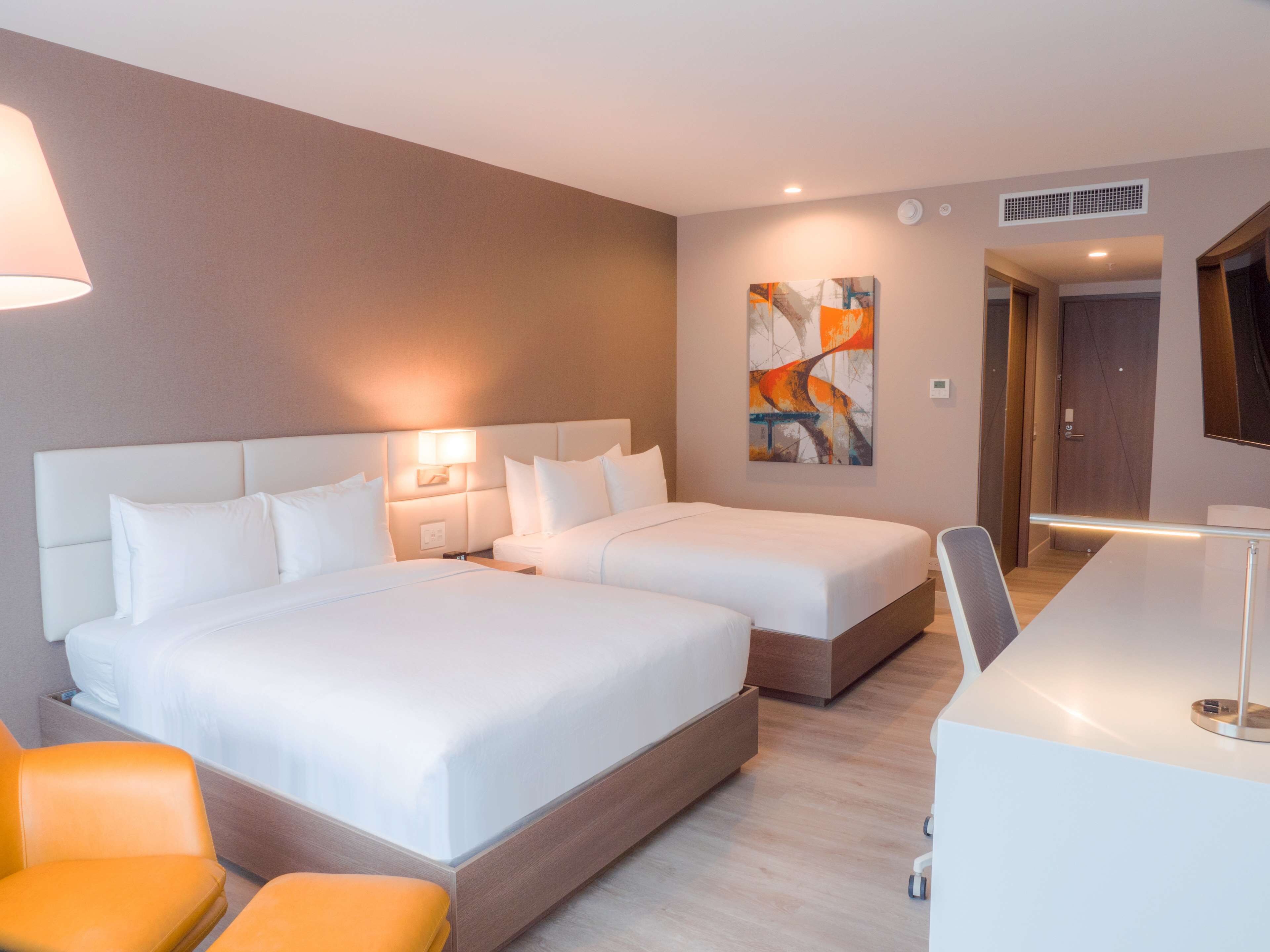 A hotel room with two beds, a desk, and a chair.