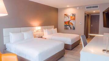 A hotel room with two beds, a desk, and a chair.