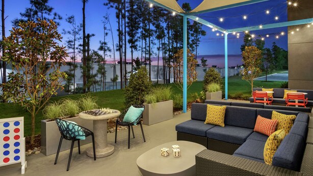An outdoor patio area with a sofa, chairs, a table, and a chessboard.