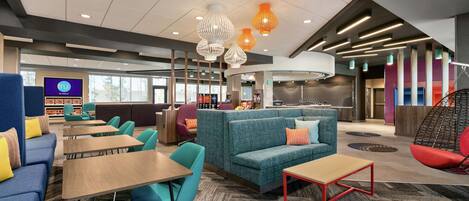 A modern lounge area with seating, tables, and a television screen displaying 'TRU by Tiffin'.