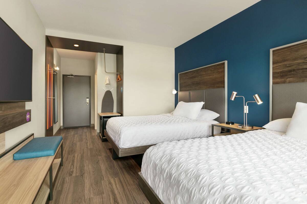 Ett hotellrum med två sängar, ett skrivbord, en bänk och en TV.