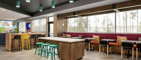 A modern restaurant with a central island, bar stools, and seating areas.