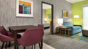 Habitación de hotel con comedor, sofá y cama.