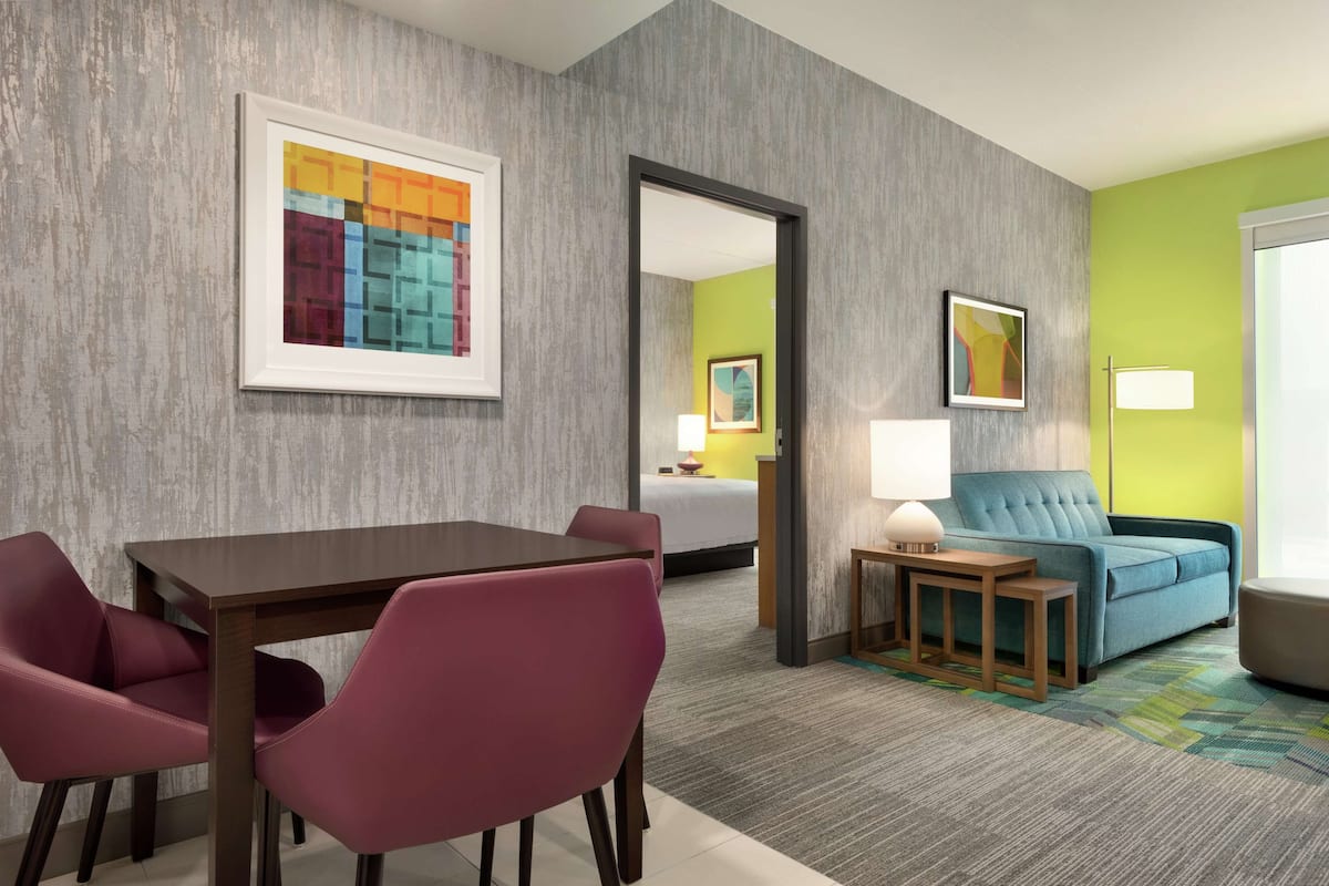 Habitación de hotel con comedor, sofá y cama.