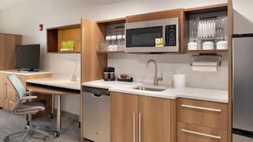 Una cocina moderna con microondas, lavamanos y armarios. Hay una cafetera y una pequeña encimera.