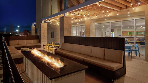 Un área de estar al aire libre con una chimenea, un sofá y una mesa.