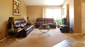 A living room with a ceiling fan, two leather sofas, a coffee table, and a TV. - Quiet neighborhood of La Canada (Tucson)