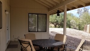 An outdoor patio with a round table and four chairs, a window, and a ceiling fan. - Quiet neighborhood of La Canada (Tucson)
