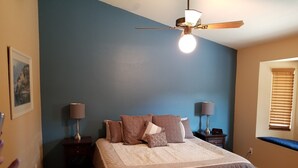 A bedroom with a bed, two bedside tables, a ceiling fan, and a window with blinds. - Quiet neighborhood of La Canada (Tucson)