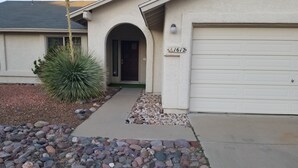 A residential house with a garage, a driveway with a stone border, and a cactus plant. - Quiet neighborhood of La Canada (Tucson)