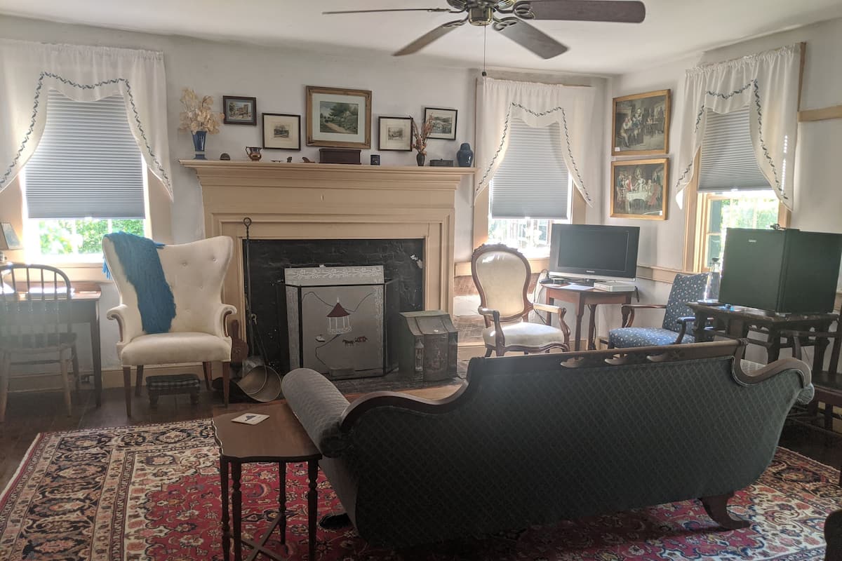 A traditional living room with a fireplace, a television, and a variety of seating options.