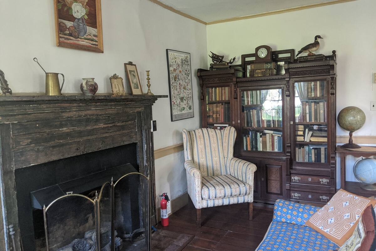 A traditional living room with a fireplace, a striped armchair, a bookshelf, and a globe on a side table.
