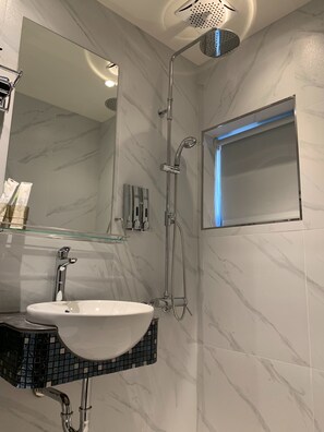 A bathroom with a white sink, a mirror, a shower with a handheld showerhead, and a small window with blue lighting. - Teeya Apartment (Taipei)