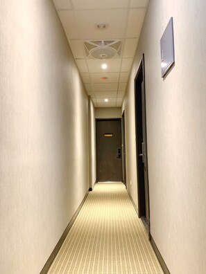 A hotel hallway with a carpeted floor, a ceiling with recessed lighting, and a door with a digital display. - Teeya Apartment (Taipei)