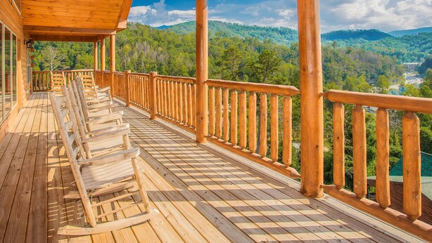 A wooden deck with a railing overlooking a forested mountain area.