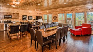 A spacious wooden cabin with a dining area, kitchen, and a red chair.