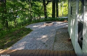 outdoor space surrounded by lush greenery and trees, featuring a wooden deck and a small circular structure.