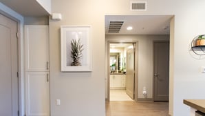 A modern kitchen with white cabinets, a framed pineapple artwork, and a wooden floor.