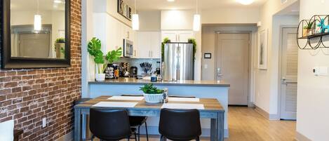 Una cocina moderna con una pared de ladrillo decorativa, una mesa de comedor con sillas y un refrigerador.
