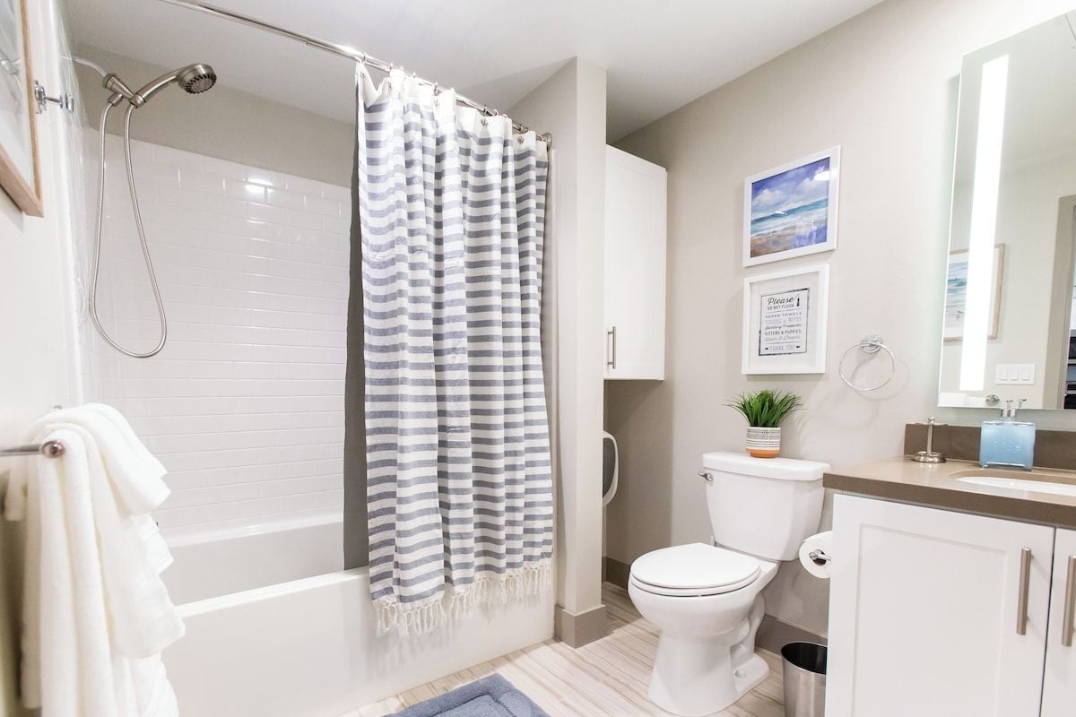 Clean full bathroom with a shower-tub combo and bright vanity