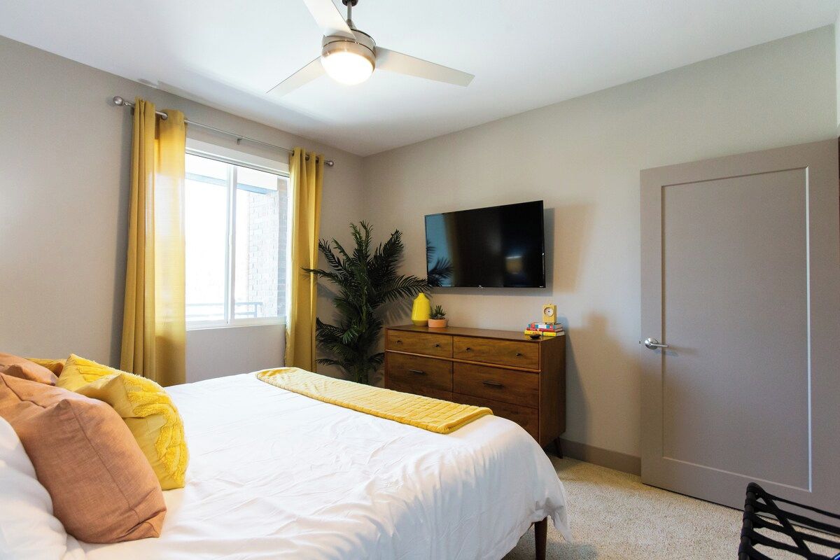 Bright bedroom with a smart TV, dresser and cheerful accents