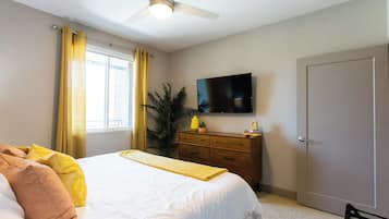 Bright bedroom with a smart TV, dresser and cheerful accents